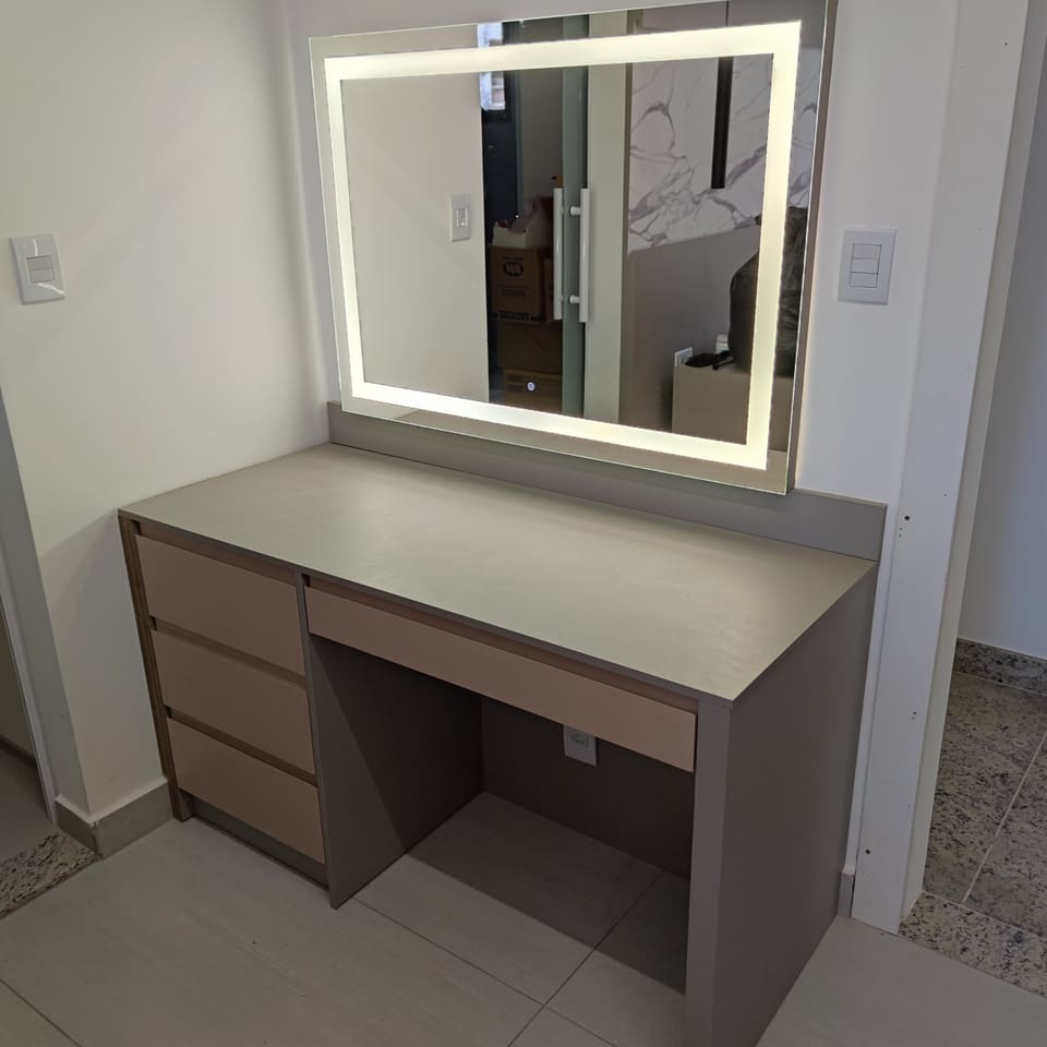 Penteadeira cinza com gavetas e espelho retangular com LED frontal aceso