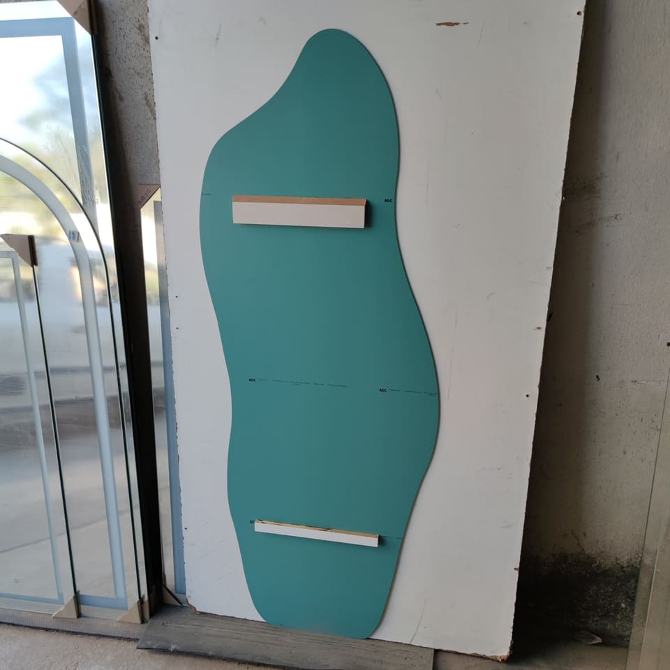 Verso de espelho orgânico pintado de verde com duas peças de fixação na horizontal